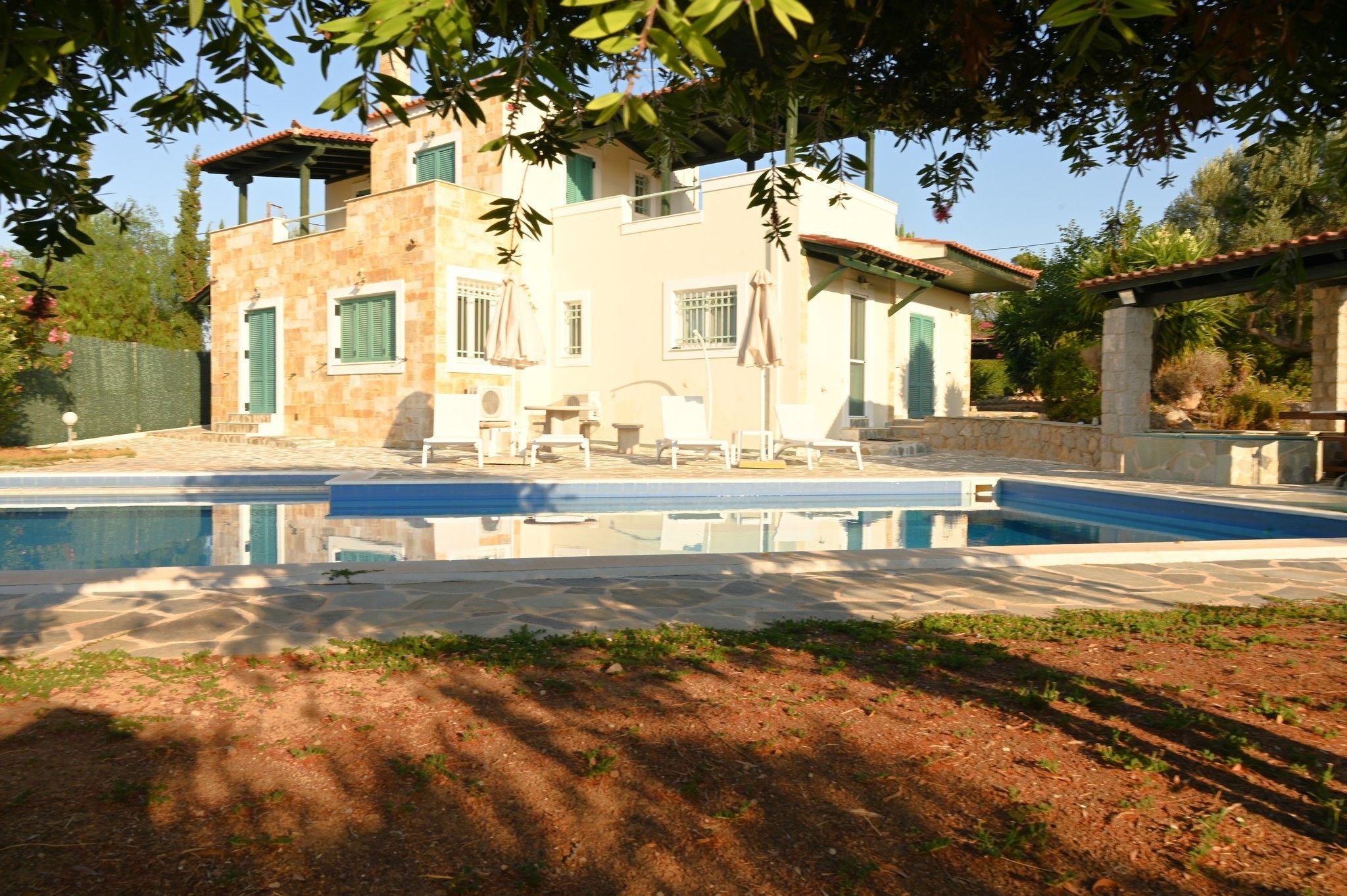 A two-story building with a swimming pool, outdoor seating, and a garden area.