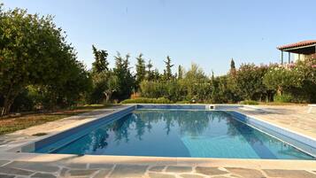 A rectangular swimming pool with clear blue water, surrounded by a stone deck.
