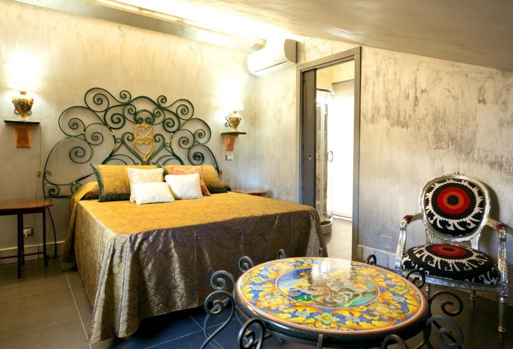 Una stanza con un letto, un tavolo rotondo e una sedia con schienale decorativo.