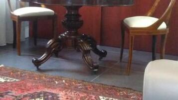 Zona pranzo con tavolo rotondo, due sedie, un vaso decorativo e un tappeto fantasia.