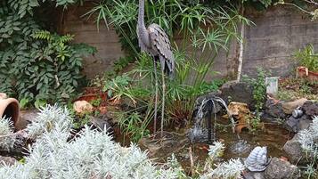 Ein Garten mit einem Wasserspiel, einem Vogel und verschiedenen Pflanzen.