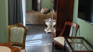 Habitación de hotel con cama, televisión, escritorio con silla, espejo y ventana con cortinas.
