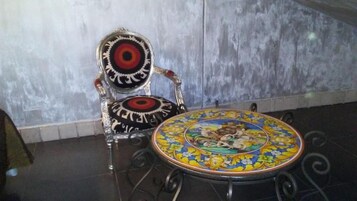 A chair with a patterned cushion and a round table with a decorative design.