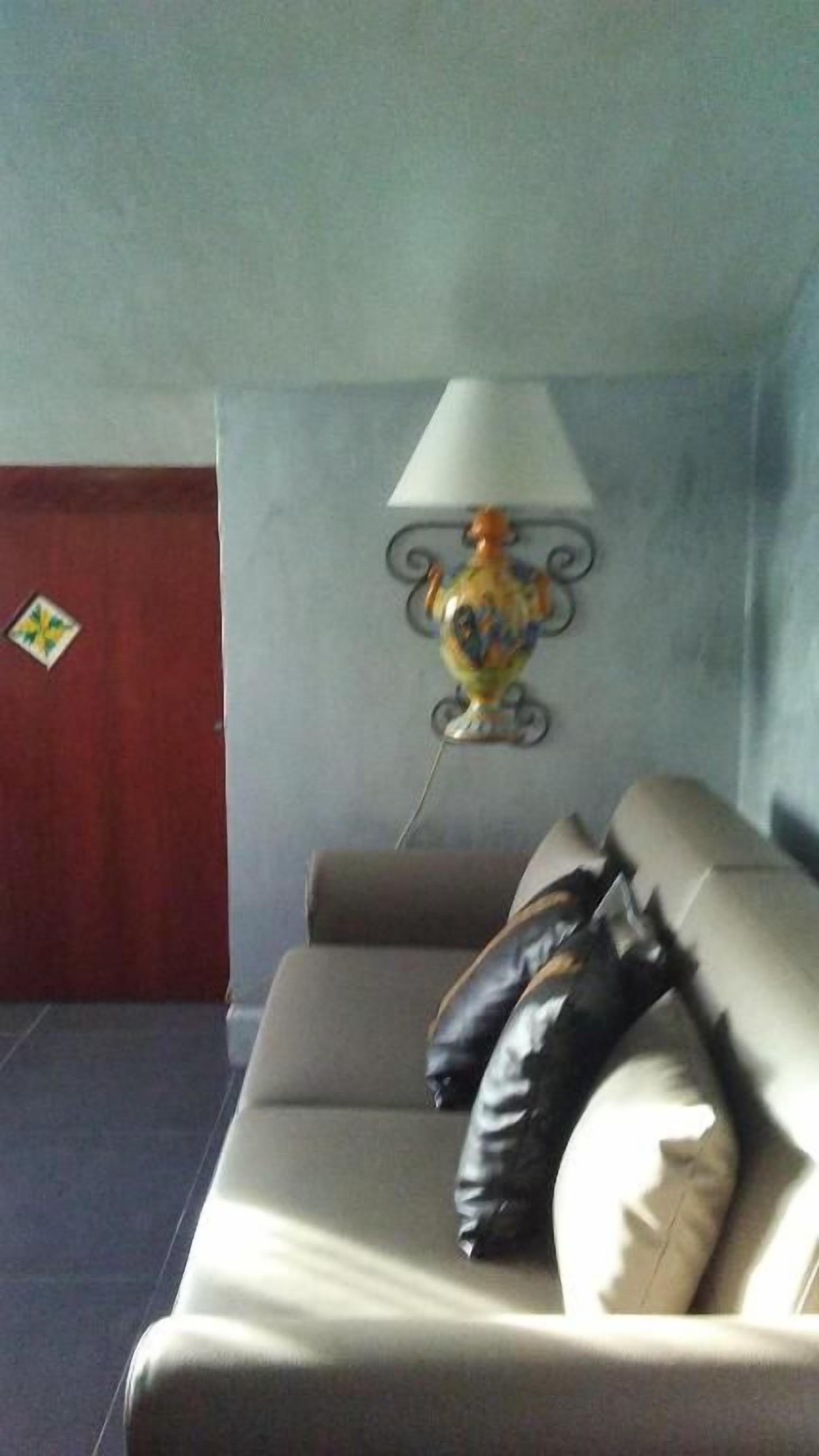 A room with a sofa, a wall-mounted lamp, and a red wall.