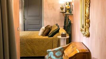 Une chambre d’hôtel avec un lit, une chaise, une petite table avec une lampe et un miroir décoratif.