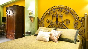 A bed with a metal headboard, a wooden wardrobe, and a bedside table with a lamp. - Animosa Suite (Castiglione di Sicilia)