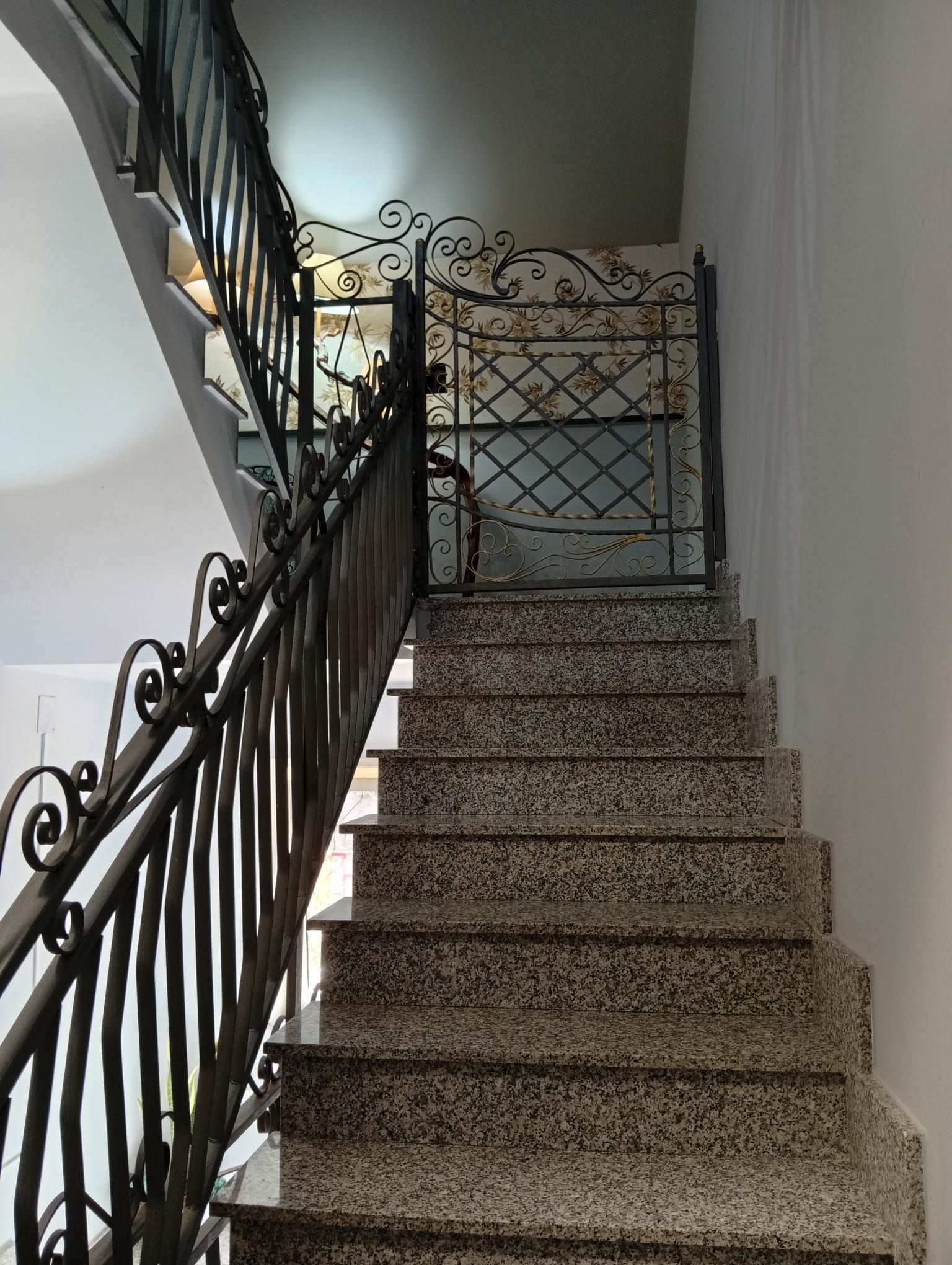 A staircase with a metal railing and a decorative gate at the top.