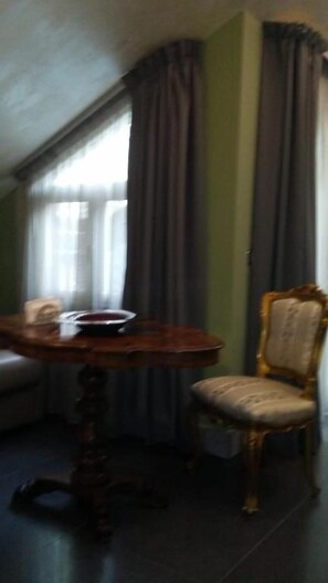 A room with a round wooden table, a chair, and a window with curtains. - Animosa Suite (Castiglione di Sicilia)