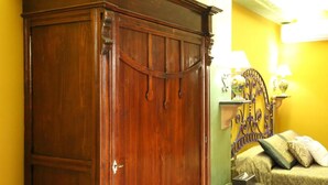A room with a wooden wardrobe, a bed with a headboard, and a small bedside table with a lamp. - Animosa Suite (Castiglione di Sicilia)