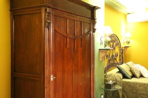 A room with a wooden wardrobe, a bed with a headboard, and a small bedside table with a lamp. - Animosa Suite (Castiglione di Sicilia)