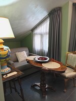 A cozy living room with a round wooden table, a sofa, a lamp, and a decorative vase.