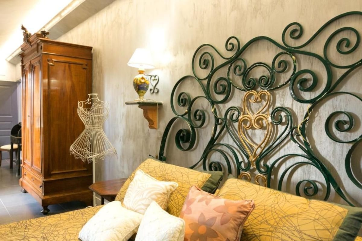 Quarto com cama, guarda-roupa de madeira e luminária na parede.
