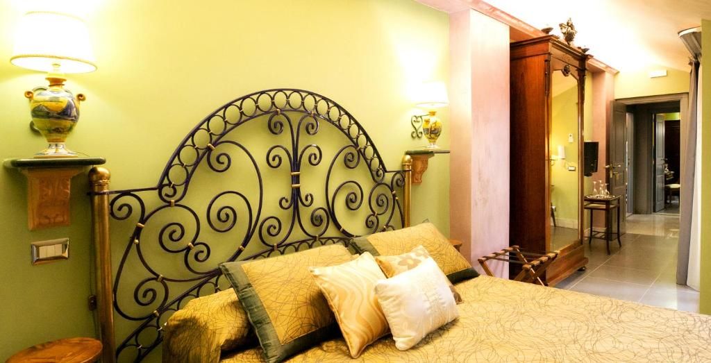 Una cama con cabecera de metal, dos lámparas de noche y una mesita de madera.