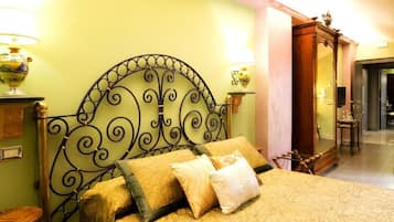 Una cama con cabecera de metal, dos lámparas de noche y una mesita de madera.