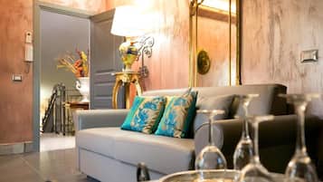 Una sala de estar con sofá, lámpara, espejo y una mesa de comedor con copas de vino.