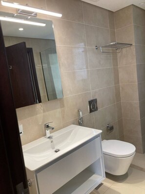 Un baño moderno con lavamanos blanco, inodoro y espejo.