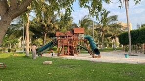 Ein Spielplatz mit einer Holzkonstruktion, Rutschen und einem Sandbereich.