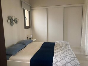 Une chambre à coucher avec un lit, une table de chevet, un miroir et une armoire.