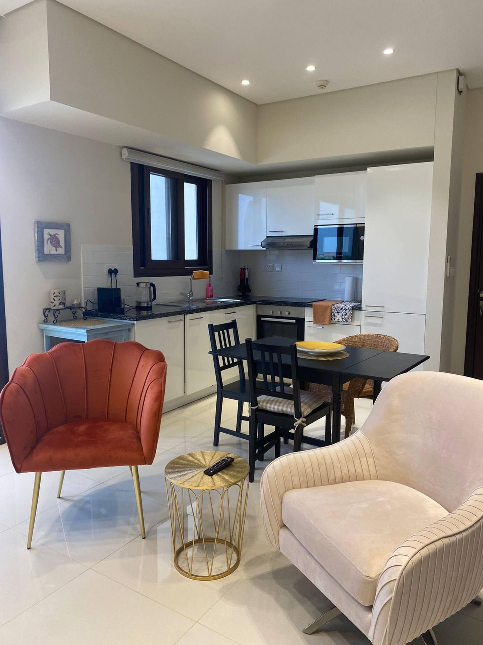 A modern kitchen with white cabinets, a black countertop, and a dining area with a table and chairs.