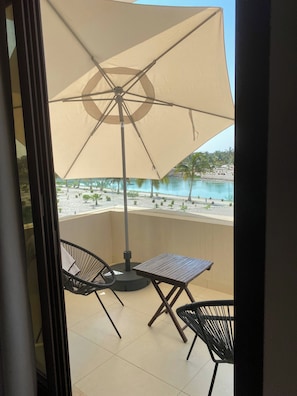 Ein Balkon mit Tisch, zwei Stühlen und einem großen Sonnenschirm.