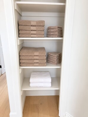 A white closet with shelves holding folded towels. - Modern 3BR Home Near CHEO & General Hospital -NO PETS (Ottawa)