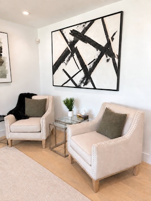 A modern living room with two armchairs, a coffee table, and a large abstract painting on the wall. - Modern 3BR Home Near CHEO & General Hospital -NO PETS (Ottawa)