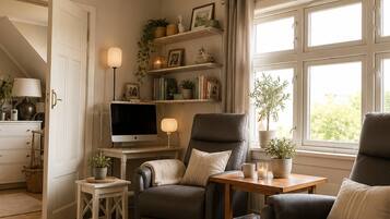 Una sala de estar con sofá, sillones, televisión y estantería.