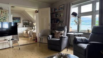 Una sala de estar con televisor, dos sillones, una mesa de centro y una estantería.