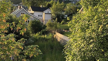 A residential area with houses surrounded by dense greenery and a clear sky.