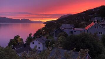 A lakeside residential area with houses, a clear sky, and a sunset.