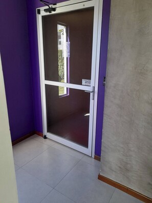 Una habitación con paredes moradas, una puerta corrediza de vidrio y piso de baldosas.