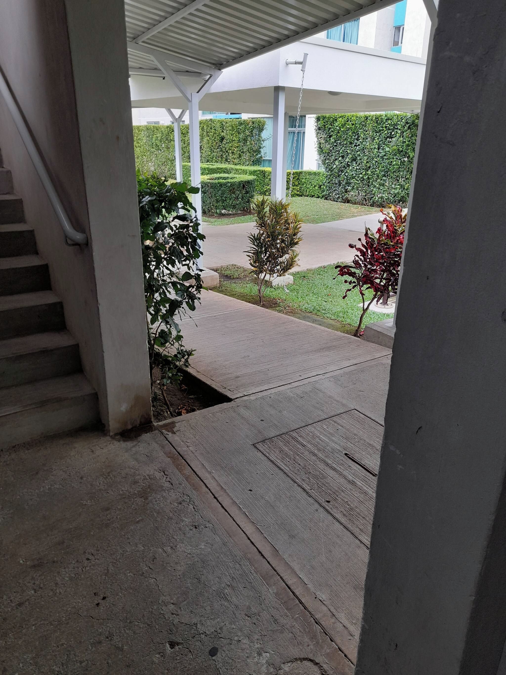 A covered outdoor area with a concrete staircase leading to a sidewalk.