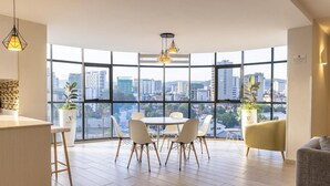Un interior moderno con comedor, ventanas amplias y vista a la ciudad.