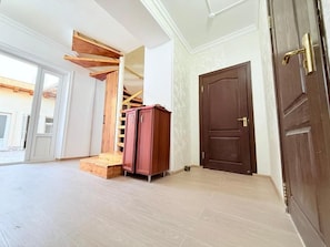 Quarto amplo com escada de madeira, uma porta grande de madeira e vista para o exterior.