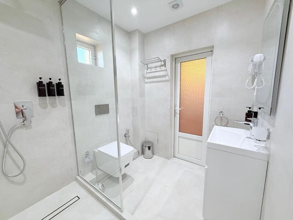 Un baño moderno con cabina de ducha de vidrio, un lavabo blanco y un espejo.