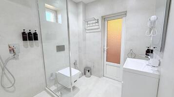 Un baño moderno con cabina de ducha de vidrio, un lavabo blanco y un espejo.