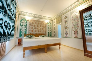 Un dormitorio con cama de madera, paredes con diseño y un taburete de madera.