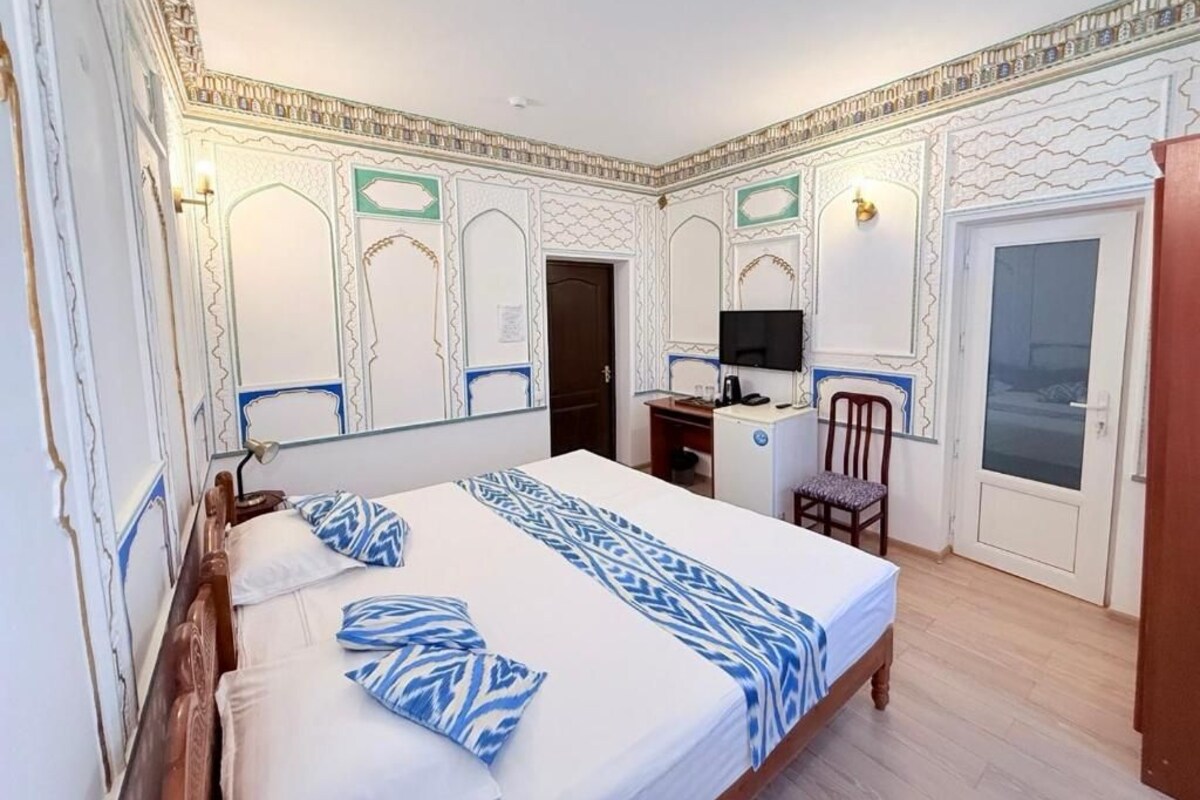 Una habitación de hotel con una cama, un escritorio, una silla y un televisor.