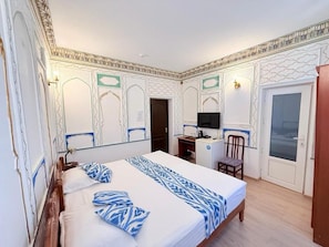 Una habitación de hotel con una cama, un escritorio, una silla y un televisor.
