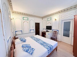 Una habitación de hotel con una cama, un escritorio, una silla y un televisor.