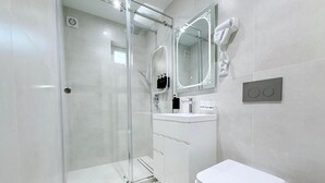 A modern bathroom with a glass shower enclosure, a white toilet, and a vanity with a mirror and hairdryer. - Ismat Premium Guest House Bukhara (Bukhara)