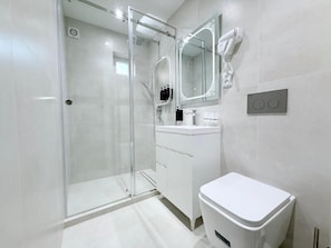 A modern bathroom with a glass shower enclosure, a white toilet, and a vanity with a mirror and hairdryer. - Ismat Premium Guest House Bukhara (Bukhara)