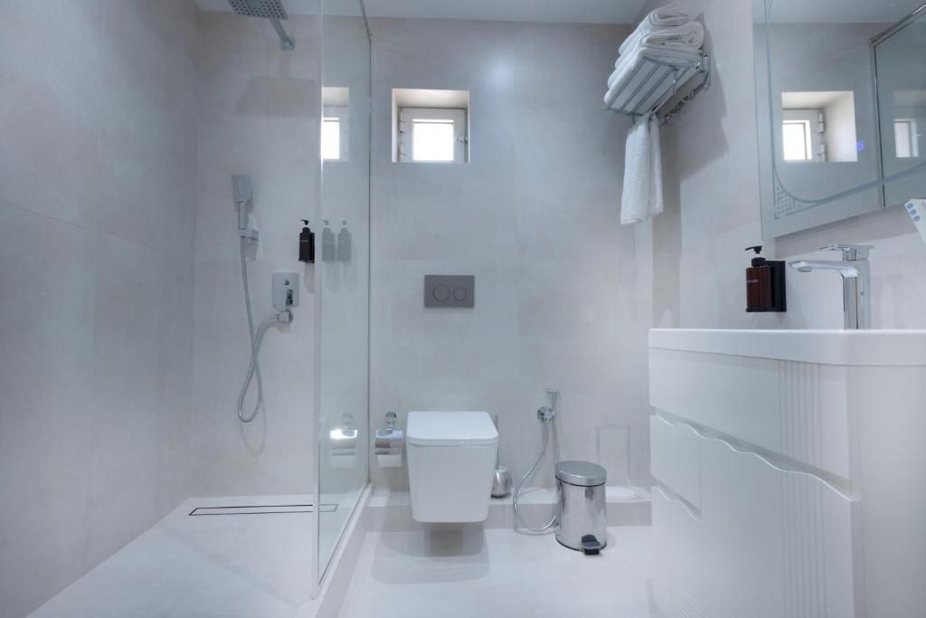 Et moderne badeværelse med brusekabine i glas, toilet, vask med spejl og håndklædestang.