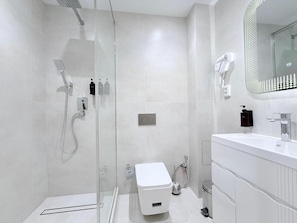 A modern bathroom with a glass shower enclosure, a white toilet, and a vanity with a mirror. - Ismat Premium Guest House Bukhara (Bukhara)