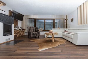 Ein modernes Wohnzimmer mit Kamin, einem weißen Sofa, einem Ledersessel und einem Holztisch.