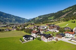 Ein Bergdorf mit traditionellen Chalets, blauem Himmel und einer kurvenreichen Straße.