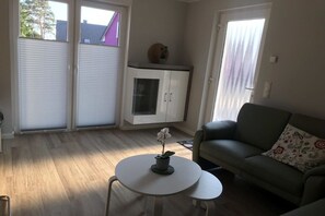 Ein Wohnzimmer mit einer Couch, einem kleinen runden Tisch mit einer Pflanze und einer Vitrine.