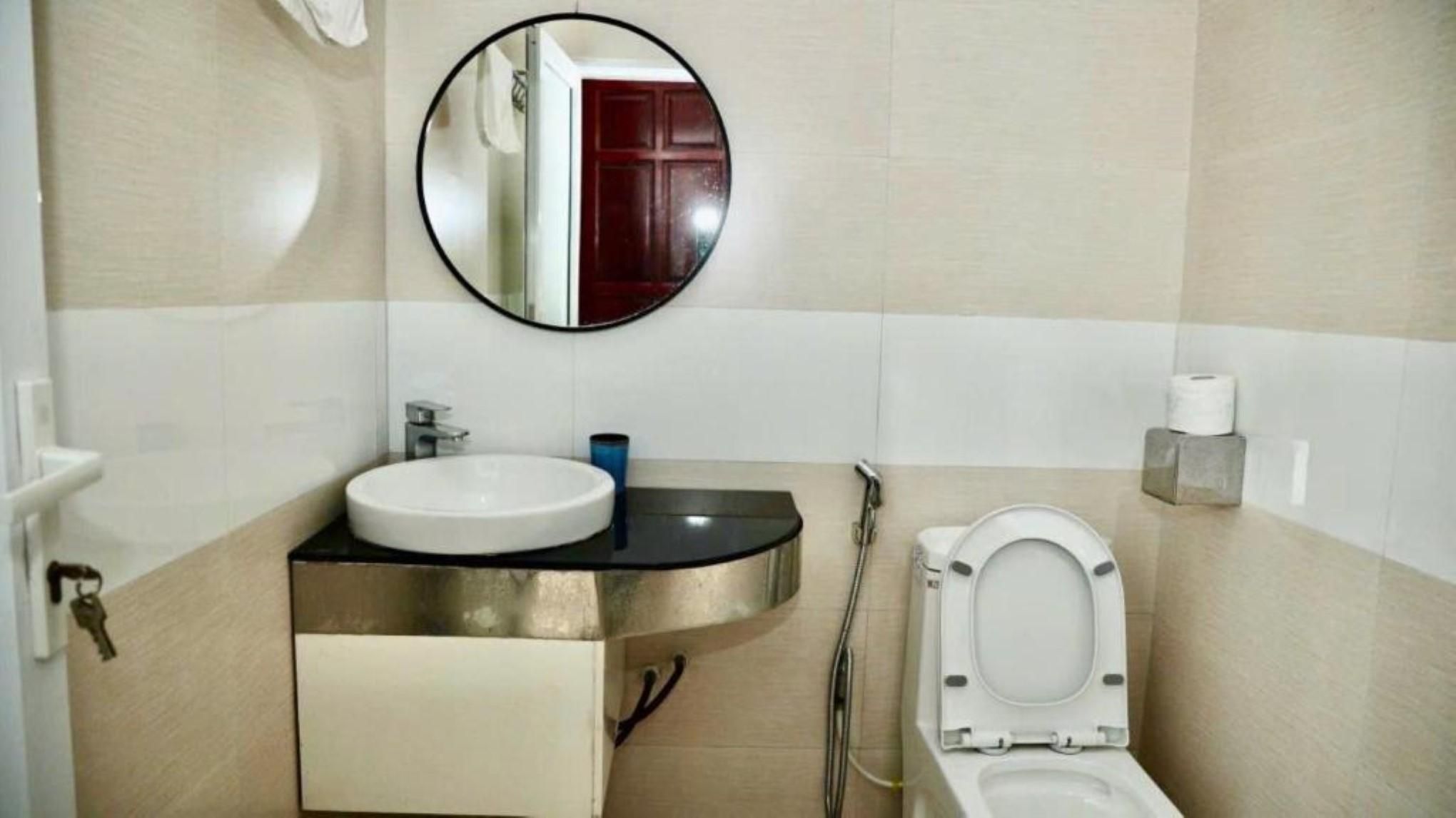 A bathroom with a sink, mirror, toilet, and towel rack.