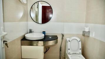 Een badkamer met een wastafel, spiegel, toilet en douche.