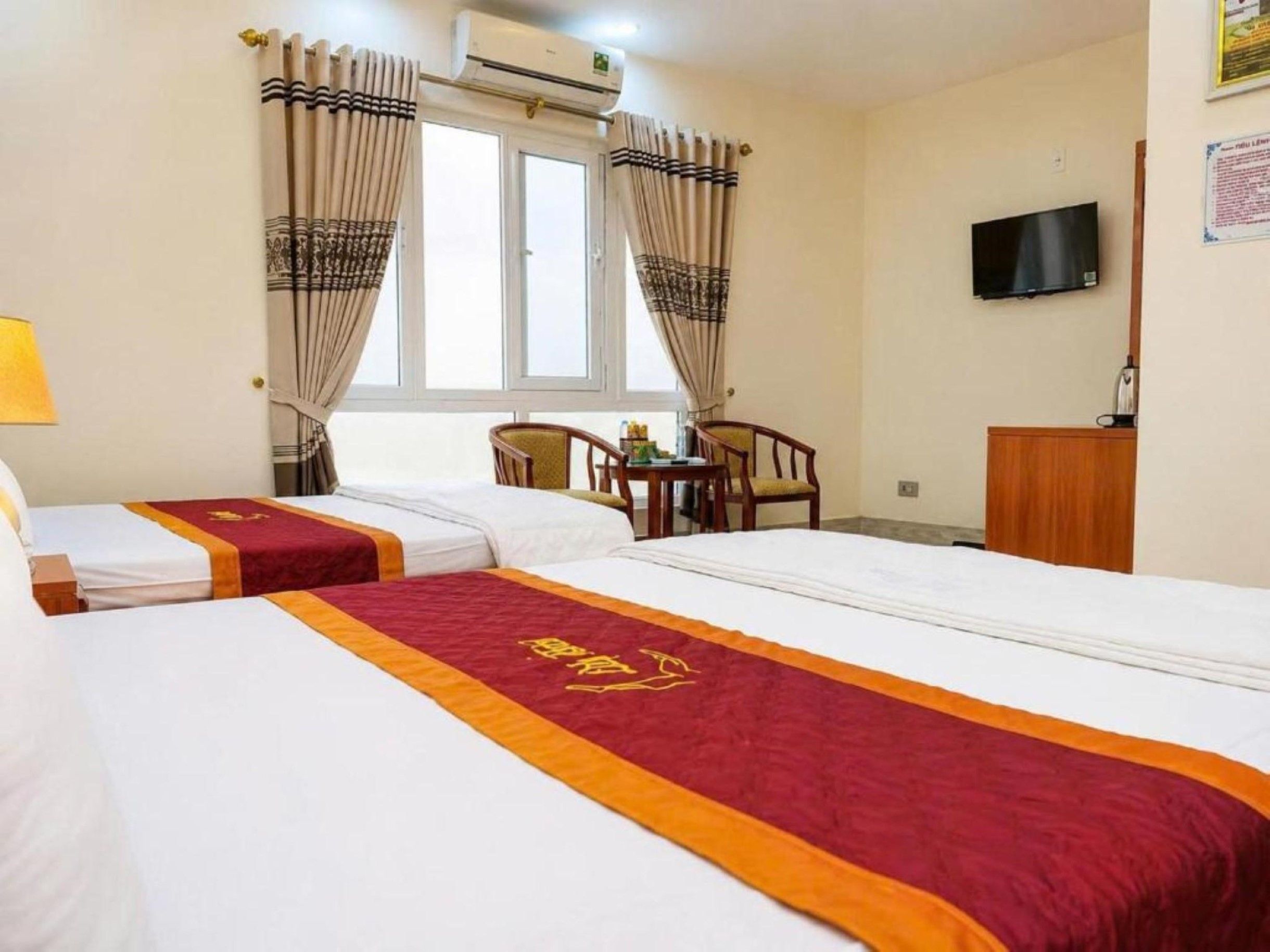 Una habitación de hotel con dos camas, televisión, escritorio y cortinas.